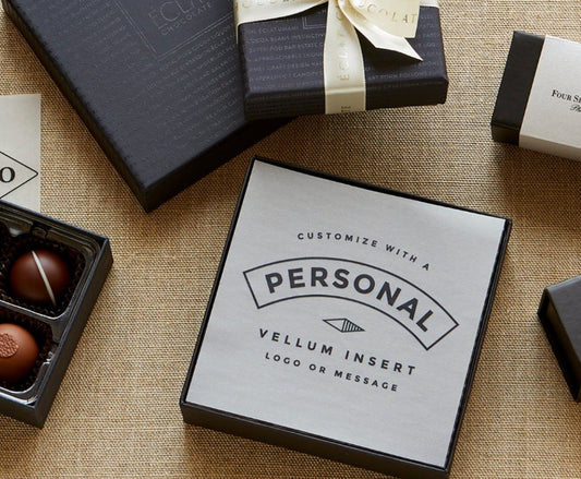 Personalized vellum insert card on a textured surface with chocolate truffles and gift boxes.