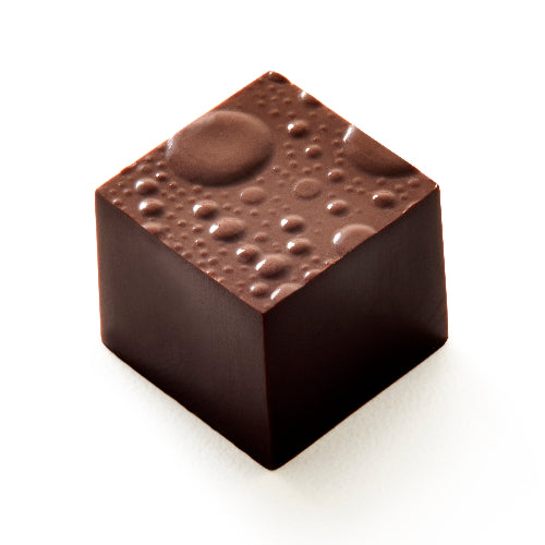 A single square dark chocolate confection with a glossy finish and small bubble-like details on top, photographed on a clean white background.
