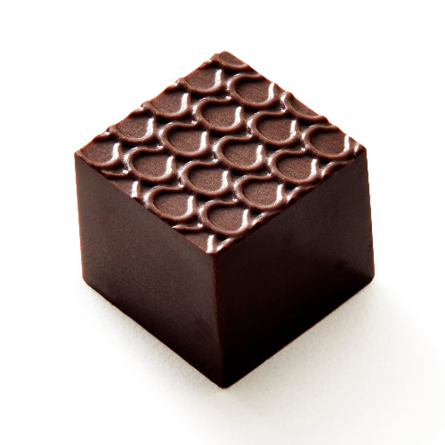 A single square dark chocolate piece with a textured pattern of circular indentations on top, photographed on a clean white background.