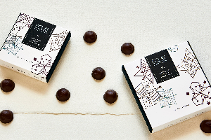 Two boxes of Eclat Chocolat with chocolate truffles on a white surface